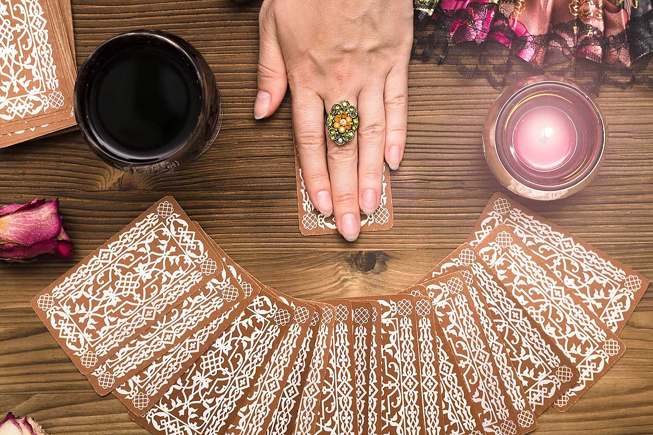 Fortune teller female hands and tarot cards on wooden table. Divination concept.