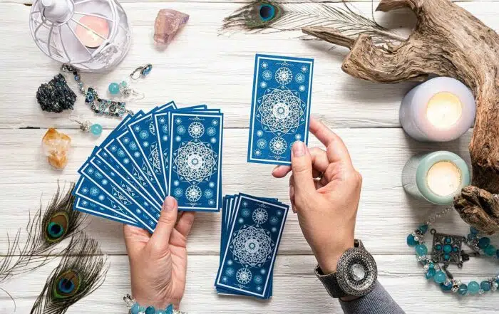 Fortune teller woman with blue tarot cards over white wooden table background.